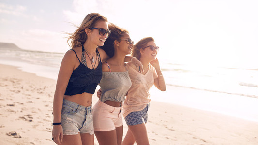 Happy young women strolling along coastline