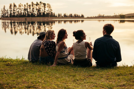 Group of young friends relaxing by a lake
