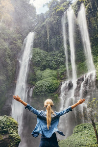 Excited woman standing by waterfall