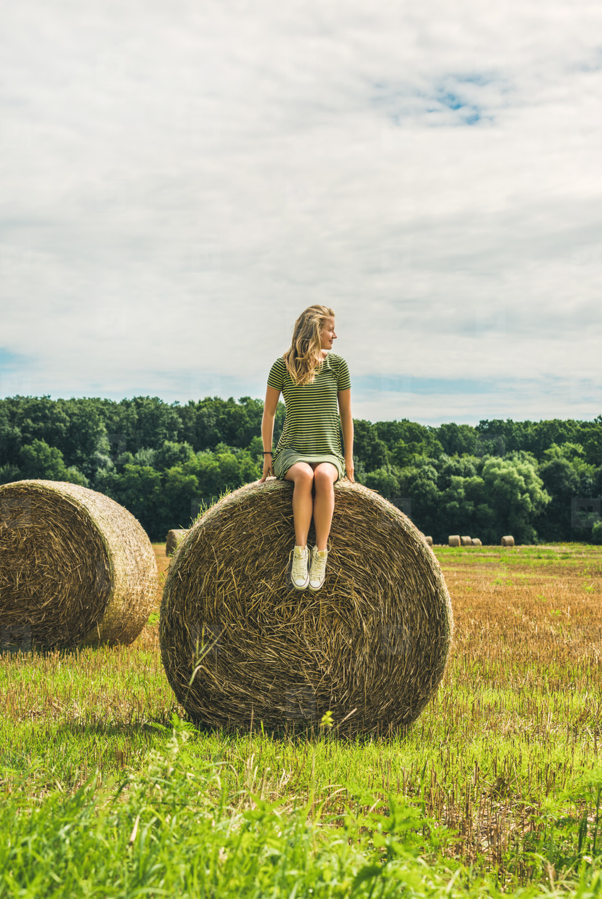Young blond lady sitting on haystack and looking away  Hungary