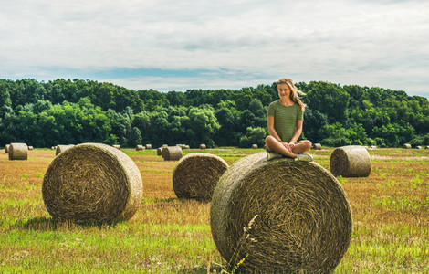 Young blond lady sitting on haystack and smiling  Hungary