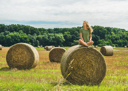 Young blond girl sitting on haystack and smiling Hungary