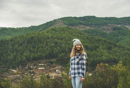 Young woman traveler in chekered shirt hiking in the mountains