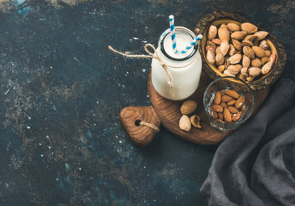 Fresh almond milk in glass bottle with almonds in bowls