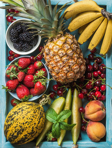Healthy summer fruit variety  Sweet cherries  strawberries  blackberries  peaches  bananas  melon slices and mint leaves