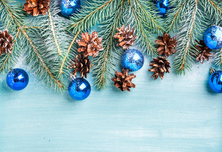 New Year or Christmas background fir branches  blue glass balls and pine cones over turquoise wooden backdrop  copy space