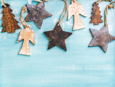 New Year or Christmas background wooden angels stars and small fir trees over blue painted backdrop copy space
