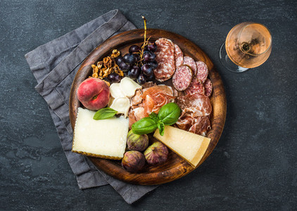Italian antipasti snack for wine on wooden tray dark background
