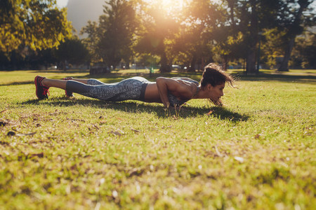 Fitness woman doing push ups exercise in a park