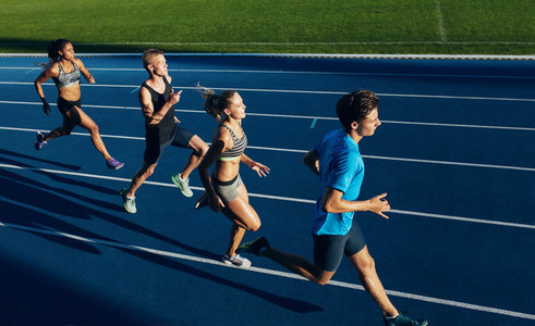 Multiracial athletes practicing running on racetrack