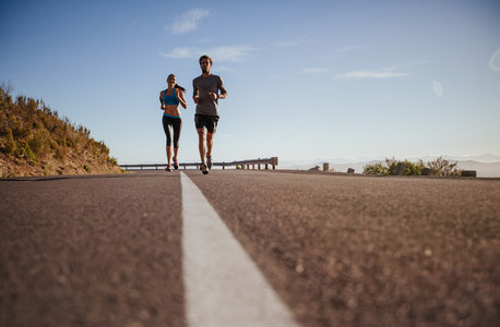 Two young people running on country road