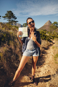 Excited young woman hiker showing a map
