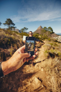 Man talking pictures of a woman with mobile phone   Hiking trip
