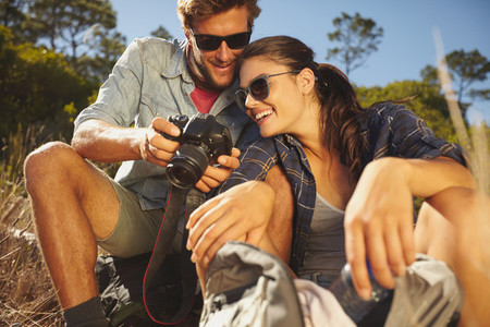 Smiling couple on a hike looking pictures on digital camera