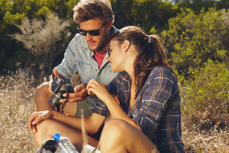 Young couple outdoors looking at pictures on digital camera