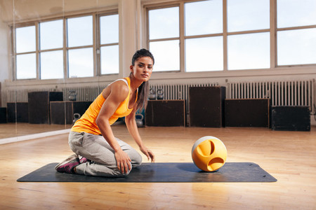 Muscular young woman exercising at gym with kettlebell