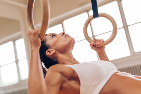 Strong woman doing pull ups with gymnastic rings