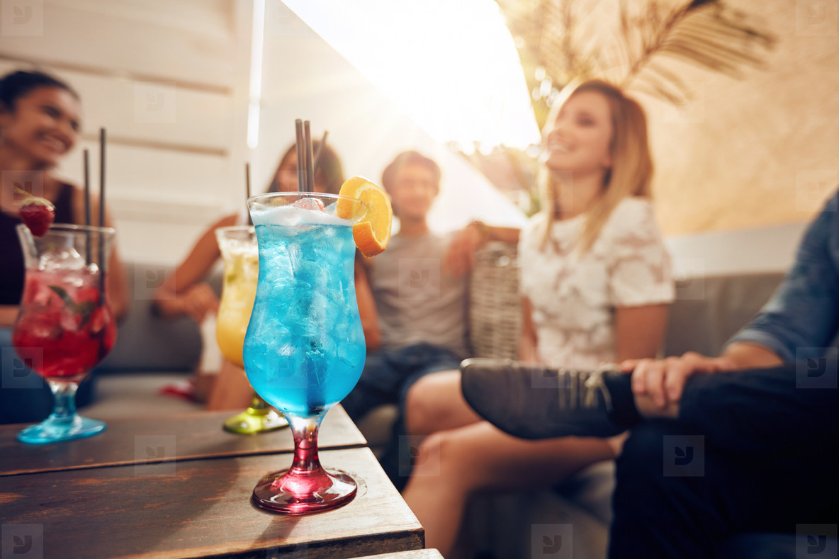 Cocktails on table with young people partying on rooftop