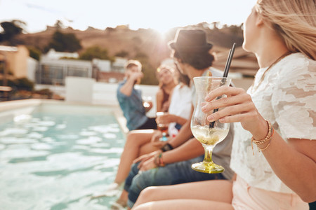 Young people enjoying a poolside party with drinks