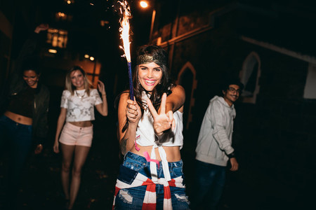 Cheerful young woman holding a sparkler enjoying in party