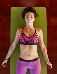 Healthy woman in savasana yoga pose at gym