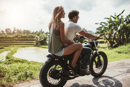 Man riding motorcycle with a woman on rural road