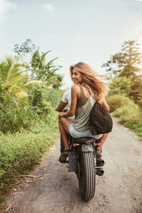 Young couple riding motorbike on dirt road
