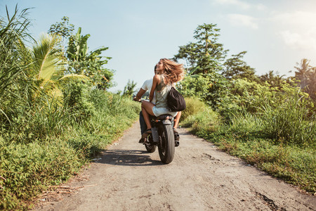 Couple riding motorcycle on rural road