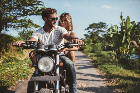 Man riding on a motorbike with girlfriend on country road
