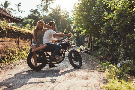 Couple hanging out with motorcycle on village road