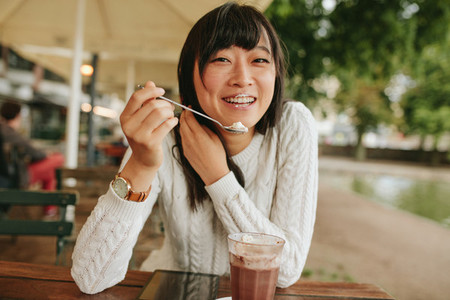 Chinese female enjoying dessert at cafe