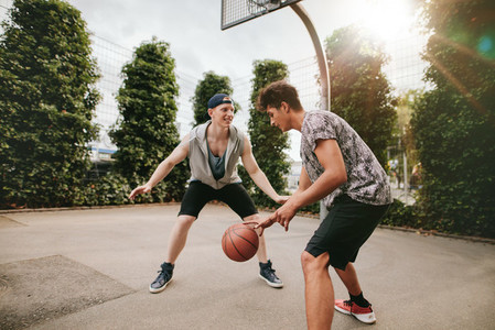 Teenagers playing basketball on outdoor court