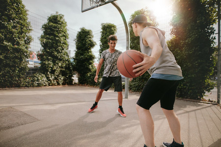 Young friends playing basketball on court