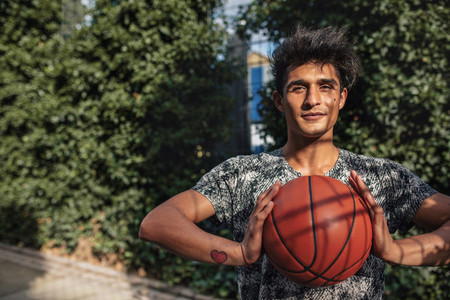 Young basketball player holding a ball on outdoor court