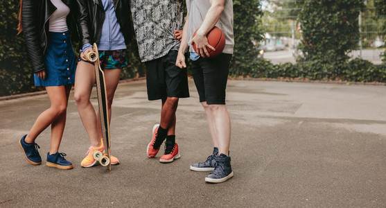 Group of people standing with basketball and skateboard