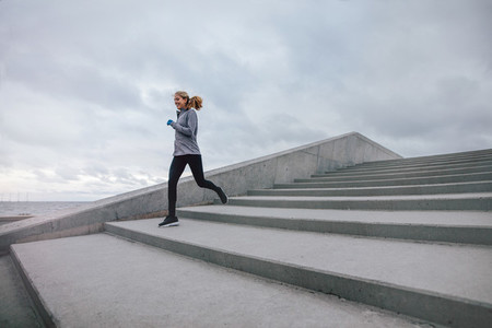 Fitness woman running down on steps