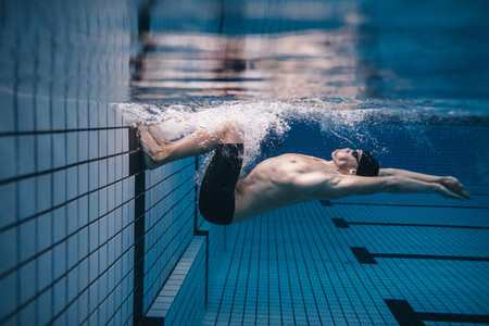 Pro male swimmer in action inside swimming pool