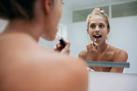 Woman putting on lipstick in bathroom