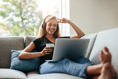 Smiling woman relaxing in living room with laptop