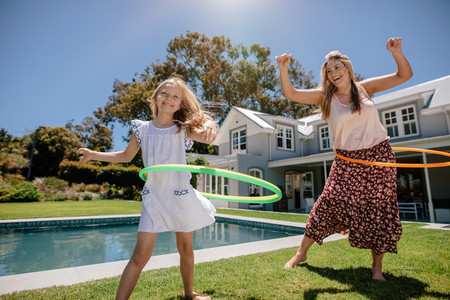 Happy mother and daughter twirling hula hoops