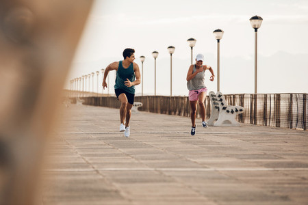 Fitness couple sprinting on the promenade