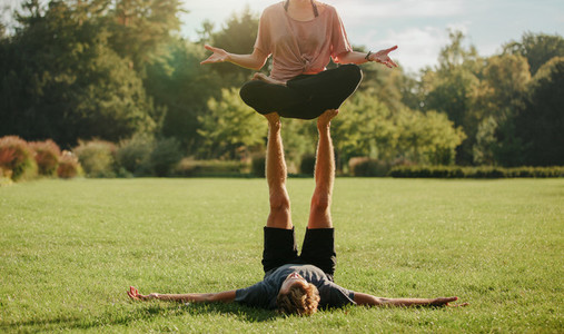 Couple in park practising pair yoga poses