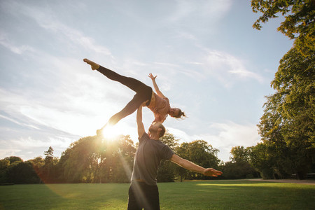 Young couple doing acroyoga at the park