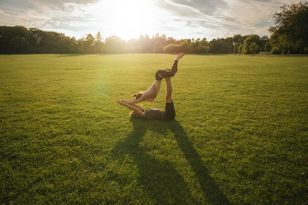 Couple doing acro yoga in lawn