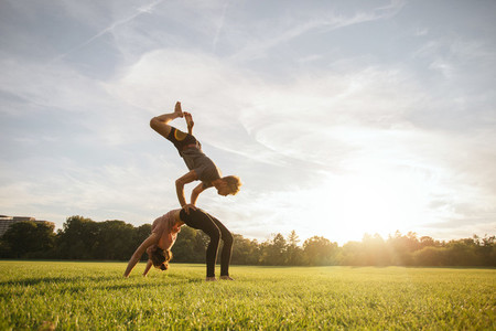 Healthy couple doing acro yoga on grass