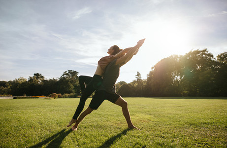 Couple doing acrobatic yoga exercise at park