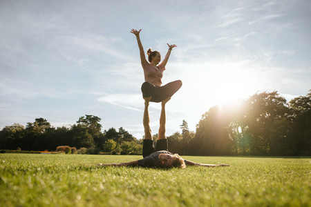 Fit couple exercising acroyoga in park