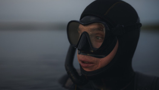 Scuba diver submerged in water looking away