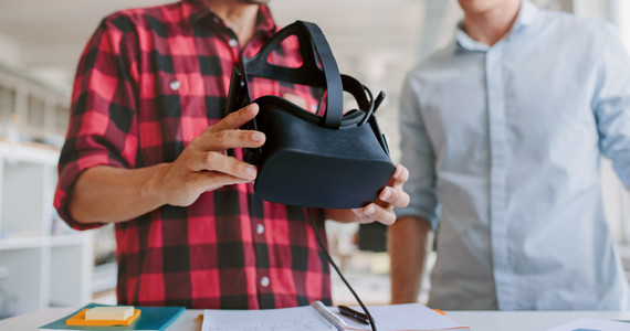 Business men working at desk holding VR glasses