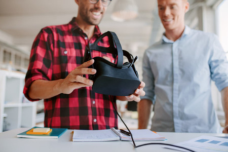 Two men using virtual reality goggles in office